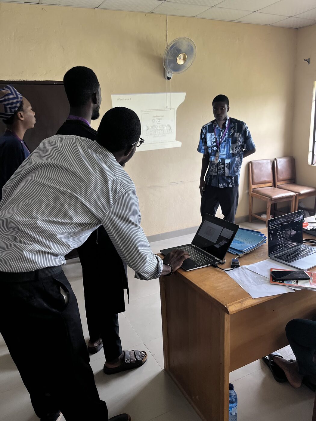 Lecturer closely inspecting student project on laptop